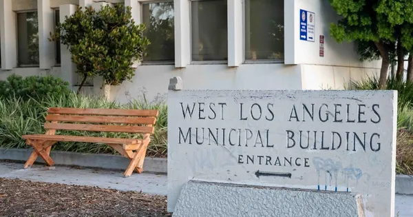 A shot of the exterior to the West Los Angeles Municipal Building with a stone sign in the foreground and a wooden bench in the background.